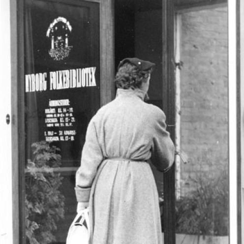 Den kvindelige låner er på vej mod bibliotekets indgangsparti …